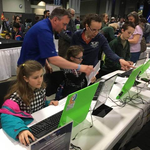 kids working on computers with adults helping them