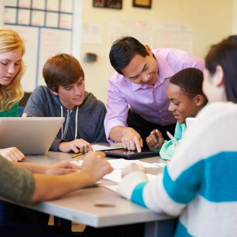 Kids around a desk in a classroom