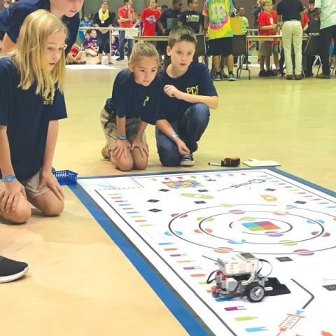 three kids working on a robotics project